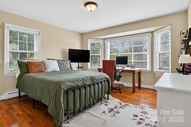 601 Pennell St NE, Lenoir, NC 28645 - bedroom with wood finished floors, multiple windows, a desk, and a baseboard radiator