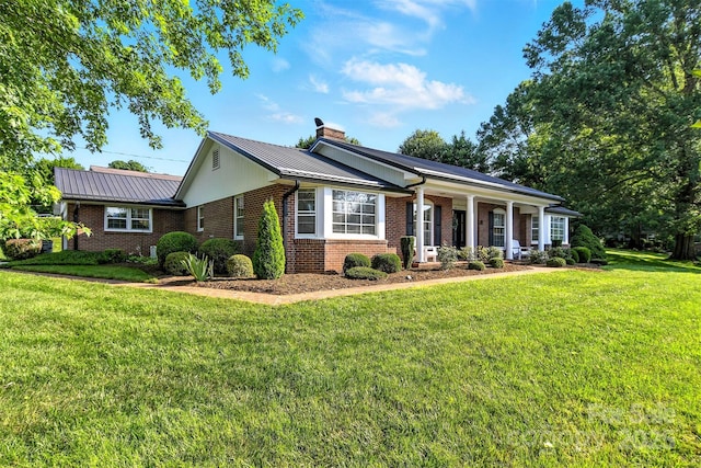 601 Pennell St NE, Lenoir, NC 28645 - ranch-style house featuring brick siding, a chimney, a front yard, a metal roof, and a porch