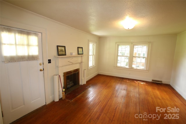 1541 Kings Rd, Shelby, NC 28150 - unfurnished living room featuring a fireplace with flush hearth, wood-type flooring, a textured ceiling, and crown molding