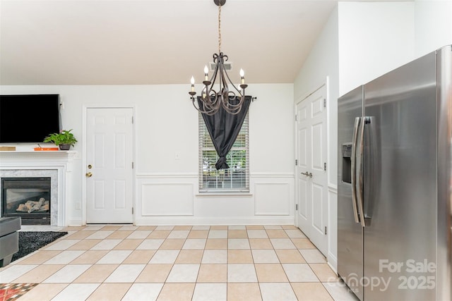 5914 Redding Rd, Charlotte, NC 28216 - unfurnished dining area featuring a chandelier, wainscoting, light tile patterned floors, and a fireplace
