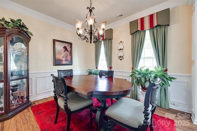 1930 Caprington Dr, Fort Mill, SC 29707 - dining area featuring a chandelier, ornamental molding, wainscoting, light wood-style flooring, and a decorative wall