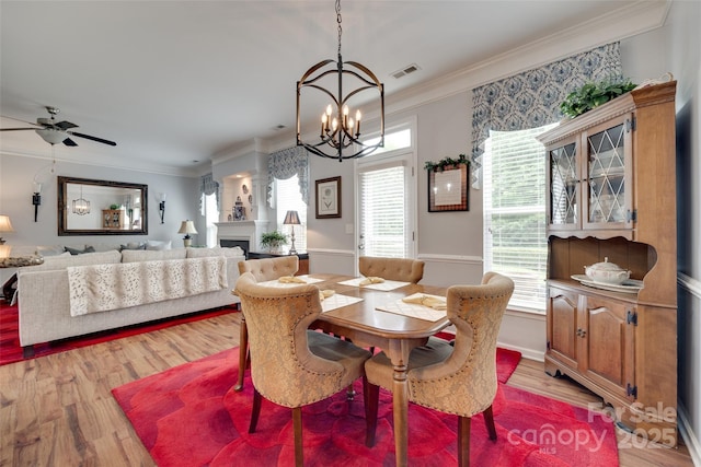 1930 Caprington Dr, Fort Mill, SC 29707 - dining area with a chandelier, light wood-type flooring, crown molding, a ceiling fan, and a fireplace