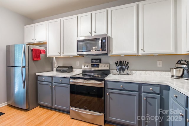 14755 Lions Paw St, Charlotte, NC 28273 - kitchen with appliances with stainless steel finishes, light wood-type flooring, white cabinetry, and gray cabinets
