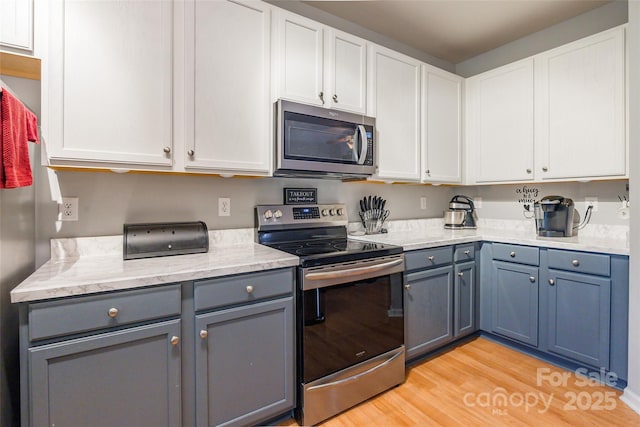 14755 Lions Paw St, Charlotte, NC 28273 - kitchen featuring stainless steel appliances, gray cabinetry, light wood-type flooring, and white cabinets