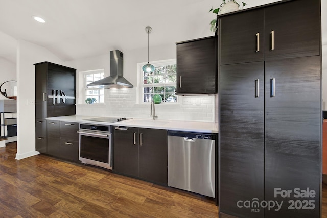 2314 Wolfe St, Charlotte, NC 28205 - kitchen featuring appliances with stainless steel finishes, wall chimney range hood, light countertops, decorative backsplash, and dark wood-style floors