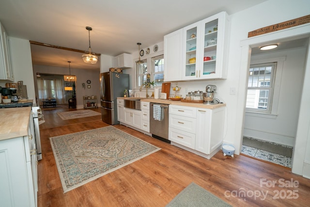 1712 Umstead St, Charlotte, NC 28205 - kitchen featuring stainless steel appliances, white cabinets, light wood-type flooring, glass insert cabinets, and decorative light fixtures