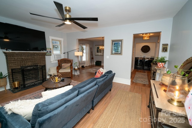 1712 Umstead St, Charlotte, NC 28205 - living room with washer and dryer, ceiling fan, wood finished floors, and a brick fireplace