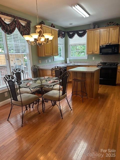 104 Whimbrel Ln, Mooresville, NC 28117 - kitchen with black microwave, gas range oven, a chandelier, light wood-style floors, and a center island