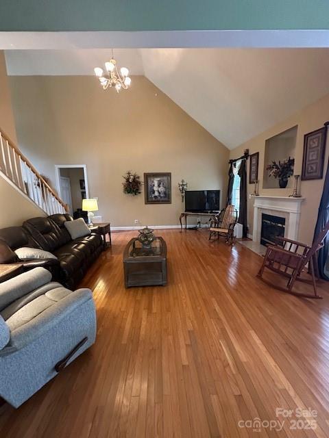 104 Whimbrel Ln, Mooresville, NC 28117 - living room featuring high vaulted ceiling, a chandelier, wood finished floors, a fireplace with flush hearth, and stairs