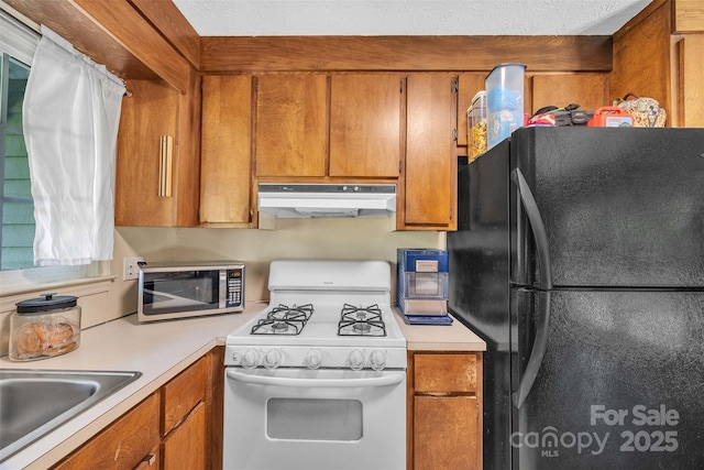 116 Eastwood Park Dr SE, Lenoir, NC 28645 - kitchen featuring freestanding refrigerator, white gas range oven, under cabinet range hood, stainless steel microwave, and light countertops