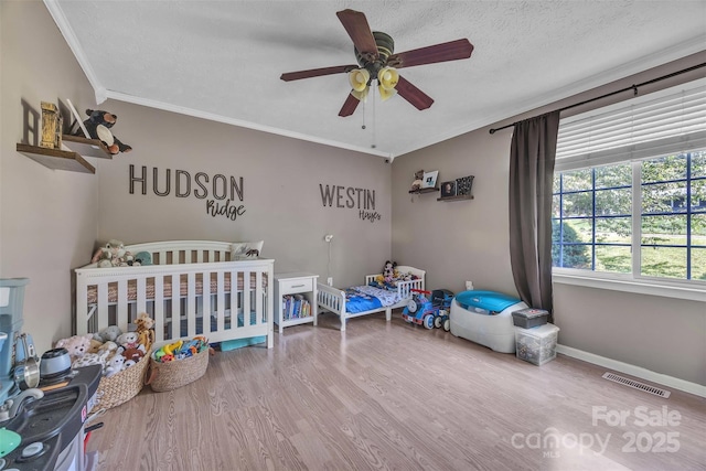 116 Eastwood Park Dr SE, Lenoir, NC 28645 - bedroom featuring wood finished floors, ornamental molding, a crib, a ceiling fan, and a textured ceiling