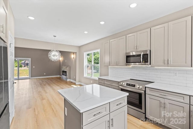 1033 12th Avenue Dr NW, Hickory, NC 28601 - kitchen featuring appliances with stainless steel finishes, decorative backsplash, a center island, a chandelier, and light wood-style floors
