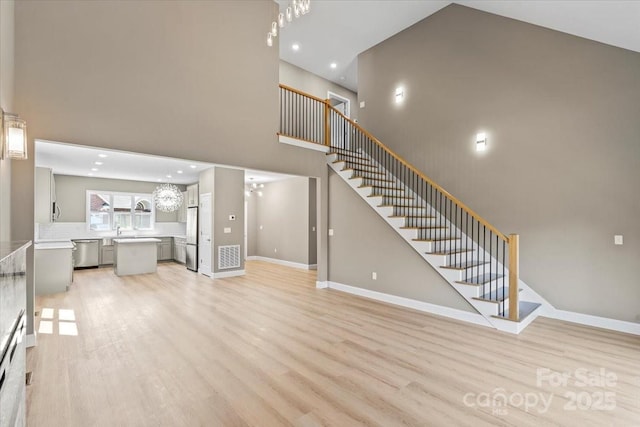 1033 12th Avenue Dr NW, Hickory, NC 28601 - unfurnished living room featuring a towering ceiling, light wood-type flooring, stairs, recessed lighting, and a chandelier