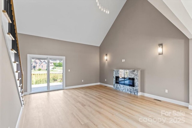 1033 12th Avenue Dr NW, Hickory, NC 28601 - unfurnished living room featuring high vaulted ceiling, light wood finished floors, a premium fireplace, and stairs