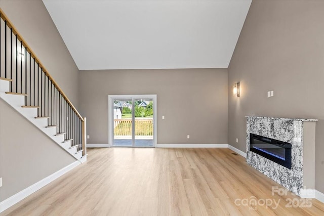 1033 12th Avenue Dr NW, Hickory, NC 28601 - unfurnished living room with wood finished floors, high vaulted ceiling, a glass covered fireplace, and stairway