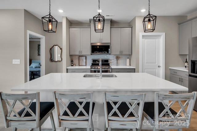 3313 Plum Dr, Monroe, NC 28110 - kitchen with stainless steel appliances, gray cabinetry, decorative backsplash, a breakfast bar, and recessed lighting