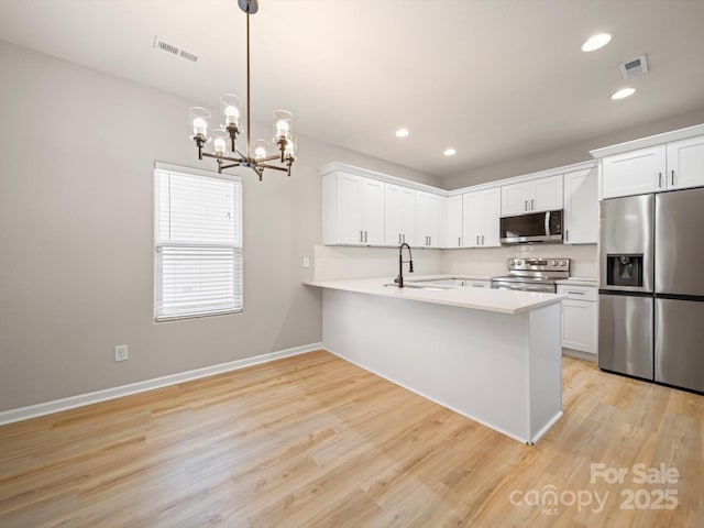 8516 Paw Valley Ln, Charlotte, NC 28214 - kitchen with stainless steel appliances, a peninsula, a chandelier, light countertops, and light wood-style floors
