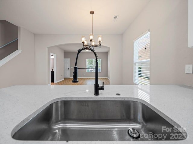 8516 Paw Valley Ln, Charlotte, NC 28214 - kitchen view of light stone countertops, hanging light fixtures, a chandelier, and arched walkways