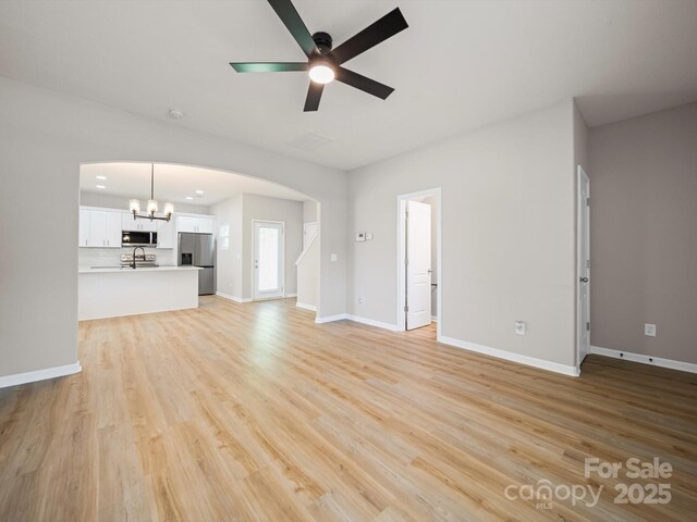 8516 Paw Valley Ln, Charlotte, NC 28214 - unfurnished living room featuring arched walkways, a ceiling fan, light wood-type flooring, and a chandelier