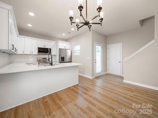 8516 Paw Valley Ln, Charlotte, NC 28214 - kitchen with stainless steel appliances, a chandelier, a peninsula, recessed lighting, and light countertops