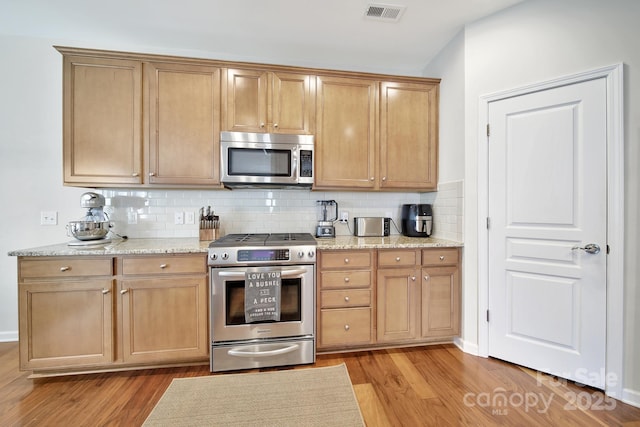 2203 Whitford Ln, Charlotte, NC 28210 - kitchen with appliances with stainless steel finishes, light wood-style floors, decorative backsplash, and light stone counters