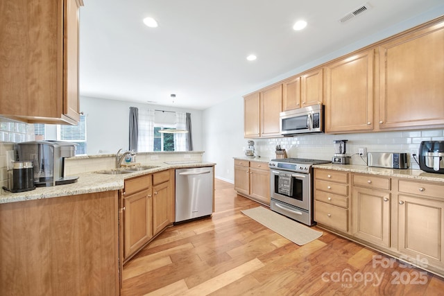 2203 Whitford Ln, Charlotte, NC 28210 - kitchen featuring appliances with stainless steel finishes, backsplash, light wood finished floors, recessed lighting, and light stone countertops
