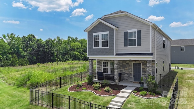 135 Orson Oaks Ln, Pineville, NC 28134 - view of front of house featuring stone siding, a fenced backyard, and covered porch