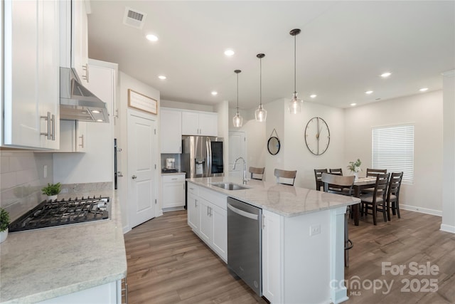 135 Orson Oaks Ln, Pineville, NC 28134 - kitchen featuring stainless steel appliances, light wood finished floors, backsplash, extractor fan, and recessed lighting