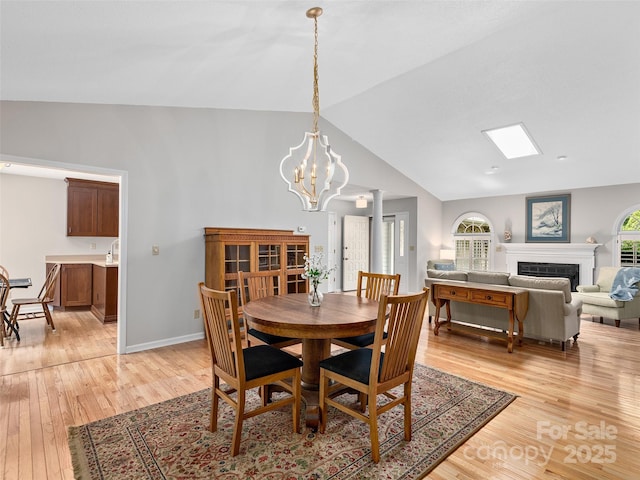 189 Cove Loop Rd, Hendersonville, NC 28739 - dining area featuring vaulted ceiling, light wood finished floors, a fireplace, and a chandelier