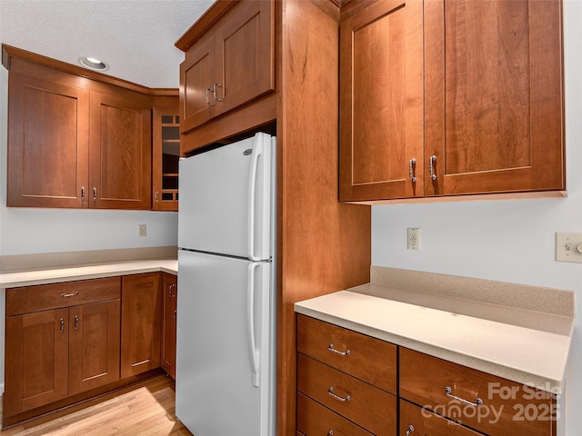 189 Cove Loop Rd, Hendersonville, NC 28739 - kitchen featuring freestanding refrigerator, brown cabinetry, light countertops, light wood-style floors, and recessed lighting