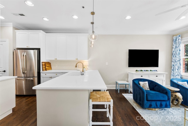 106 N Laurel Ave Unit 118, Charlotte, NC 28207 - kitchen featuring freestanding refrigerator, ornamental molding, a kitchen breakfast bar, light countertops, and dark wood finished floors