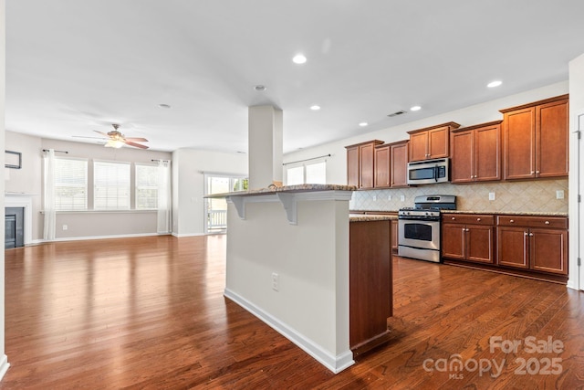 159 E Warfield Dr, Mooresville, NC 28115 - kitchen with appliances with stainless steel finishes, dark wood finished floors, decorative backsplash, a kitchen breakfast bar, and recessed lighting