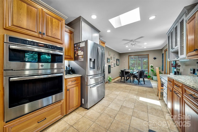 23 Indigo Way, Hendersonville, NC 28739 - kitchen featuring appliances with stainless steel finishes, a skylight, recessed lighting, brown cabinetry, and light stone counters