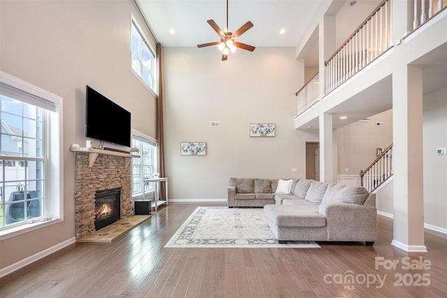 2960 Haley Cir, Davidson, NC 28036 - living room with a towering ceiling, ceiling fan, wood-type flooring, a stone fireplace, and stairs