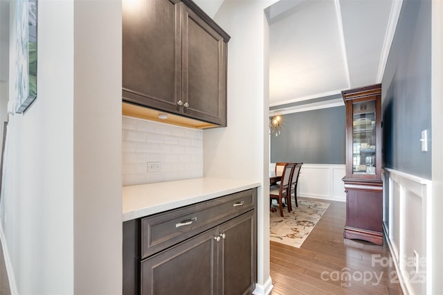 2960 Haley Cir, Davidson, NC 28036 - kitchen featuring wood finished floors, dark brown cabinets, wainscoting, light countertops, and backsplash