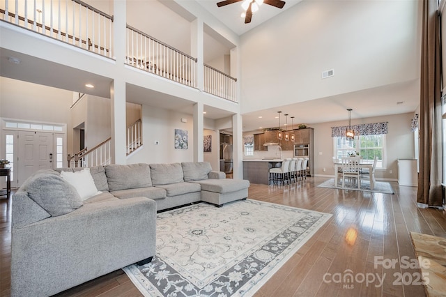 2960 Haley Cir, Davidson, NC 28036 - living room featuring ceiling fan, dark wood-style floors, a high ceiling, and stairs
