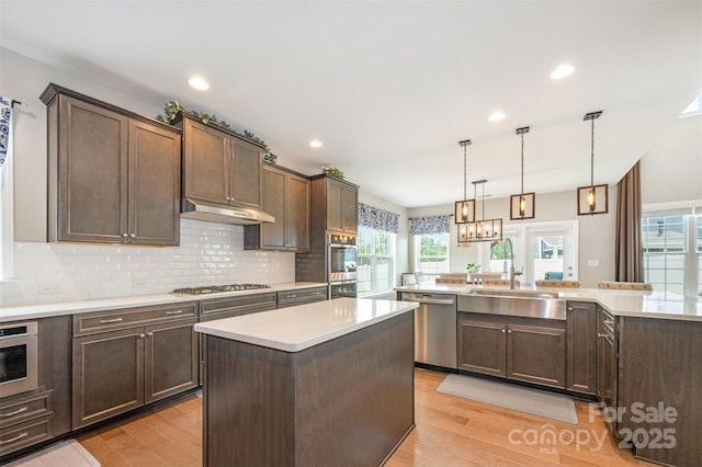 2960 Haley Cir, Davidson, NC 28036 - kitchen featuring appliances with stainless steel finishes, a kitchen island, light wood-style floors, under cabinet range hood, and backsplash