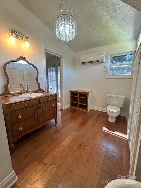 743 S College Ave, Newton, NC 28658 - bathroom with a wall unit AC, wood-type flooring, vanity, a chandelier, and a textured ceiling