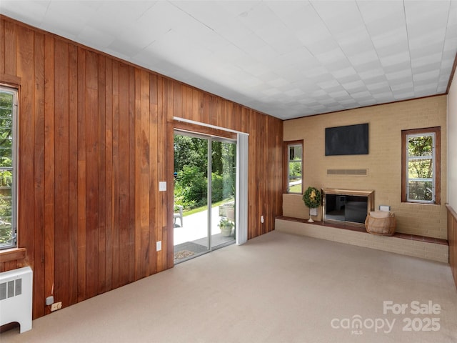 50 Skyland Ter, Canton, NC 28716 - unfurnished living room featuring radiator heating unit, a brick fireplace, carpet flooring, and wood walls