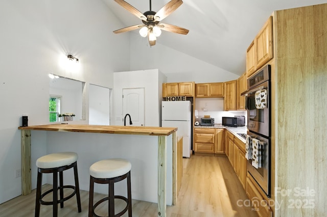 1036 Williamsburg Dr, Lenoir, NC 28645 - kitchen featuring freestanding refrigerator, high vaulted ceiling, light wood finished floors, a breakfast bar area, and a ceiling fan
