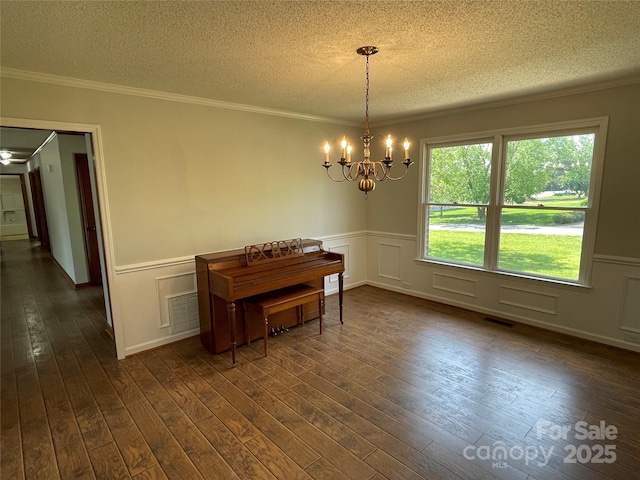2515 Myra Ln, Lincolnton, NC 28092 - dining room featuring a textured ceiling, a chandelier, dark wood-style floors, ornamental molding, and wainscoting