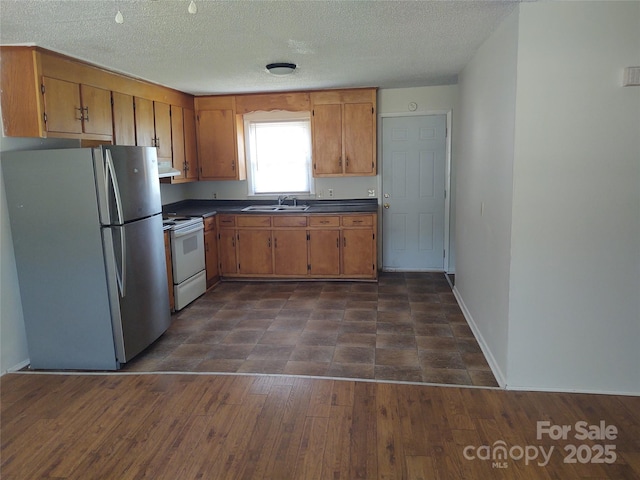 2100 Airport Rd, Salisbury, NC 28147 - kitchen featuring freestanding refrigerator, electric stove, dark countertops, brown cabinetry, and under cabinet range hood