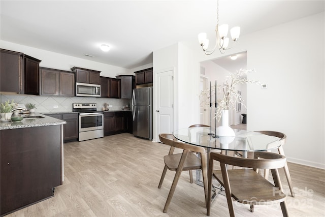 12548 Gotland Rd Unit 327, Midland, NC 28107 - kitchen with appliances with stainless steel finishes, dark brown cabinets, a chandelier, light wood-style floors, and decorative backsplash