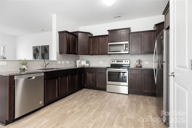 12548 Gotland Rd Unit 327, Midland, NC 28107 - kitchen featuring stainless steel appliances, stone countertops, light wood-style flooring, dark brown cabinetry, and decorative backsplash