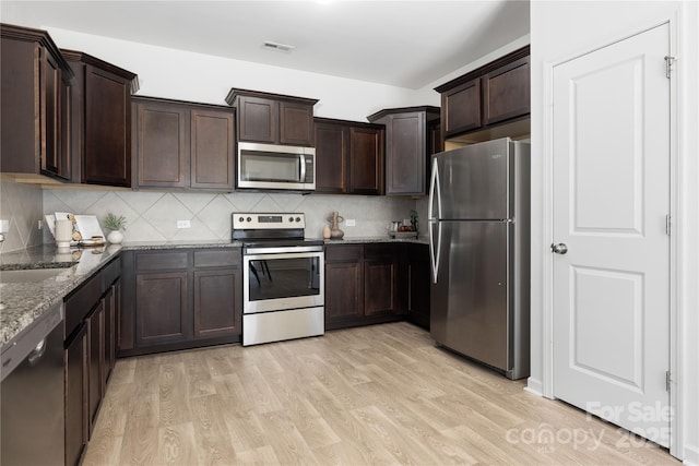 12548 Gotland Rd Unit 327, Midland, NC 28107 - kitchen featuring appliances with stainless steel finishes, dark stone countertops, light wood finished floors, and dark brown cabinetry