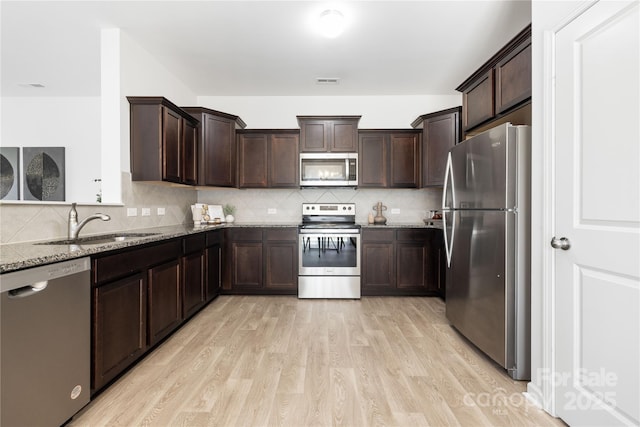 12548 Gotland Rd Unit 327, Midland, NC 28107 - kitchen with appliances with stainless steel finishes, stone countertops, light wood-style flooring, dark brown cabinets, and decorative backsplash