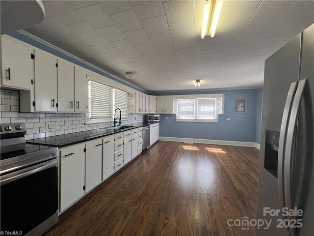 820 Suncrest Orchard Rd, North Wilkesboro, NC 28659 - kitchen with appliances with stainless steel finishes, dark countertops, decorative backsplash, white cabinets, and dark wood finished floors
