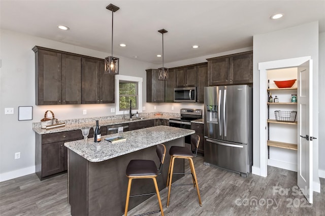 11 S Pine Dr, Weaverville, NC 28787 - kitchen featuring stainless steel appliances, dark brown cabinetry, wood finished floors, a center island, and light stone counters