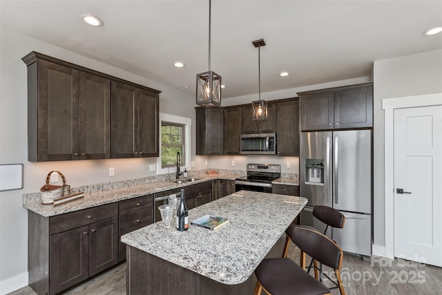 11 S Pine Dr, Weaverville, NC 28787 - kitchen featuring appliances with stainless steel finishes, light wood-type flooring, dark brown cabinetry, a kitchen bar, and light stone counters