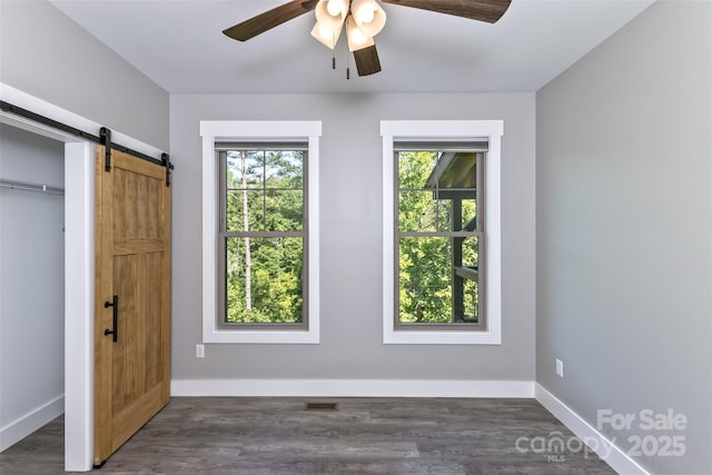 11 S Pine Dr, Weaverville, NC 28787 - unfurnished bedroom with a barn door, dark wood-style flooring, ceiling fan, and a closet